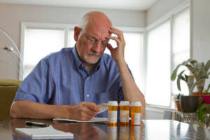 An older man with prescription medications to emphasize men's health.